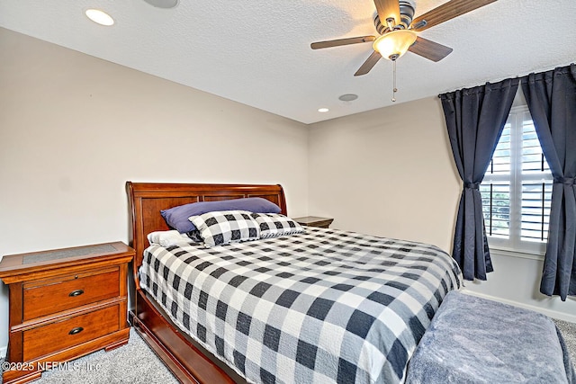 bedroom with light colored carpet, ceiling fan, and a textured ceiling