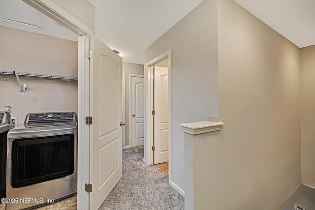 hall with a textured ceiling, carpet floors, washer / dryer, and baseboards