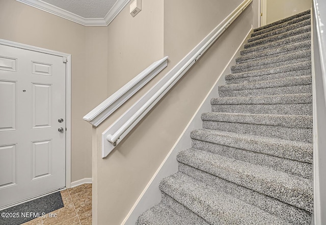 stairs with a textured ceiling, ornamental molding, and tile patterned flooring