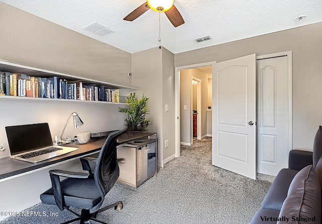 office area with light colored carpet, ceiling fan, visible vents, and a textured ceiling