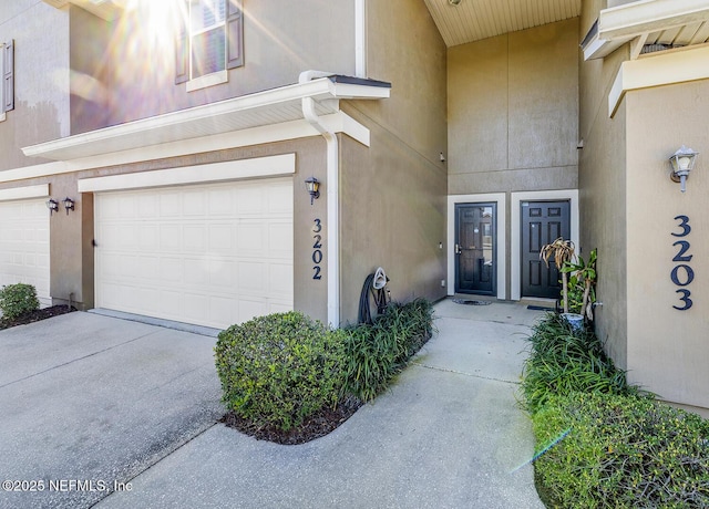 view of exterior entry with driveway and stucco siding