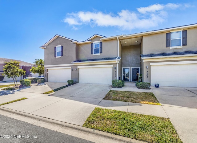 view of front of home with driveway, an attached garage, and stucco siding