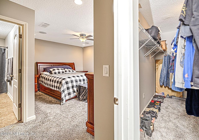 bedroom with a ceiling fan, carpet, visible vents, and a textured ceiling