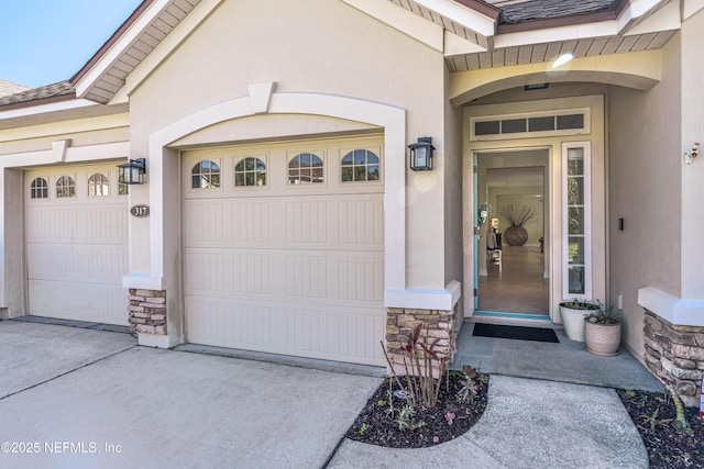 property entrance with stone siding, an attached garage, and stucco siding