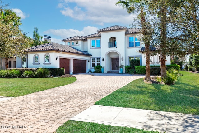 mediterranean / spanish house with a garage, a front lawn, a chimney, and decorative driveway