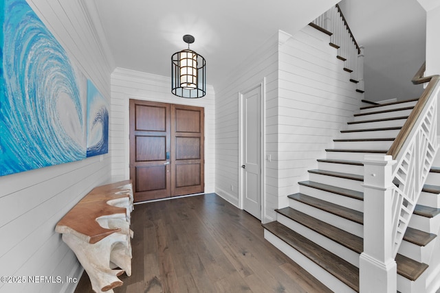 foyer with stairway, a chandelier, wood finished floors, and ornamental molding