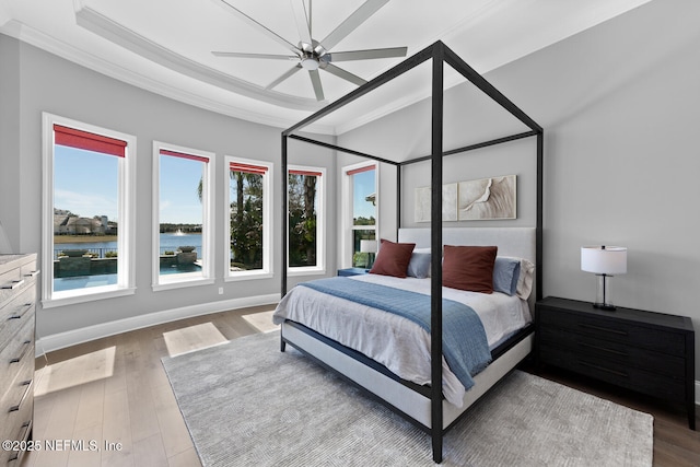 bedroom with ornamental molding, a water view, baseboards, and wood finished floors