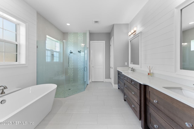 bathroom featuring a stall shower, a soaking tub, visible vents, and a sink