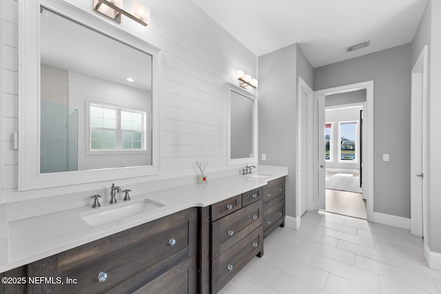 bathroom featuring double vanity, baseboards, visible vents, and a sink