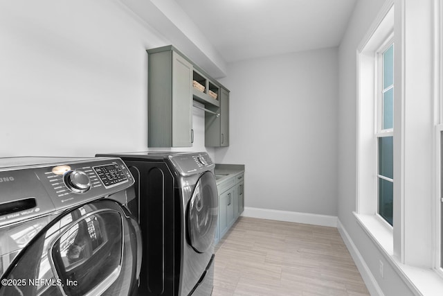 laundry area featuring cabinet space, baseboards, and independent washer and dryer