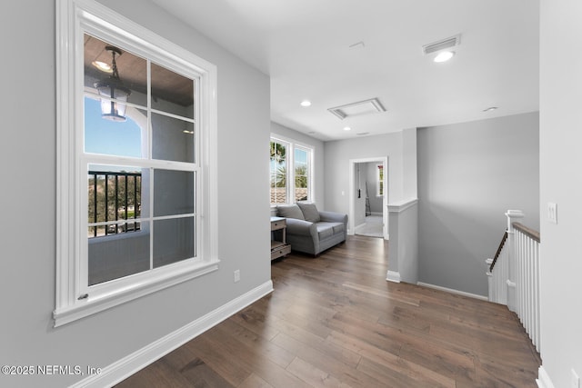 hallway with wood finished floors, an upstairs landing, visible vents, and baseboards