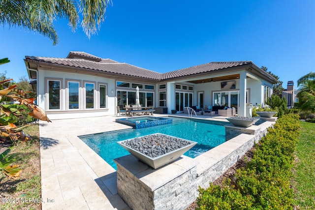 back of property featuring a tile roof, an outdoor hangout area, and stucco siding