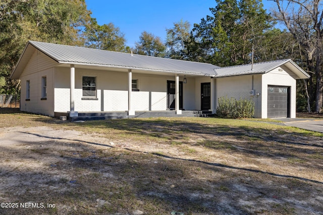 ranch-style house with brick siding, metal roof, driveway, and an attached garage