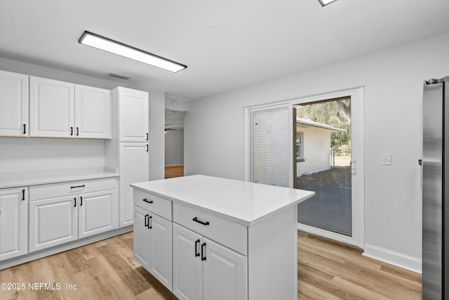 kitchen with light wood-type flooring, freestanding refrigerator, and light countertops