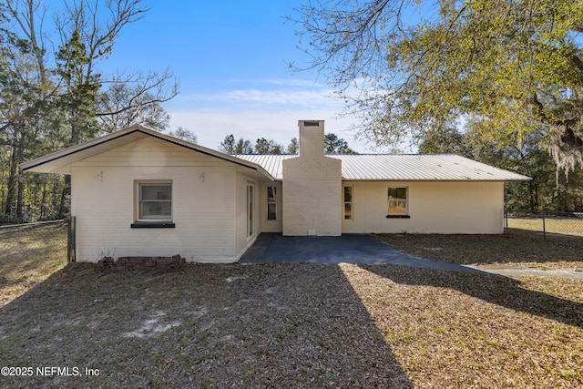 back of house with metal roof, a chimney, a patio, and fence