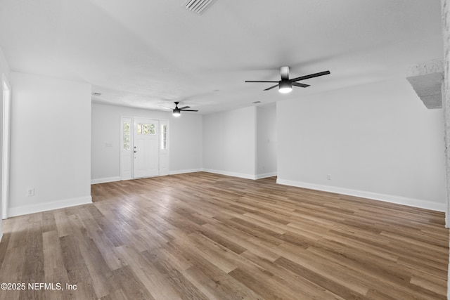 unfurnished living room featuring a ceiling fan, visible vents, baseboards, and wood finished floors