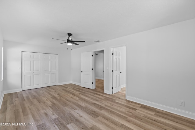 unfurnished bedroom with light wood-type flooring, a closet, ceiling fan, and baseboards