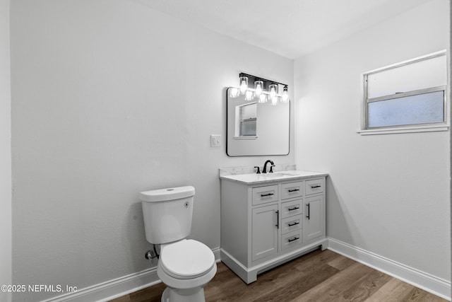 bathroom with vanity, wood finished floors, toilet, and baseboards