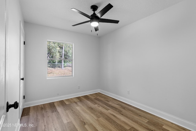 empty room with ceiling fan, a textured ceiling, wood finished floors, and baseboards