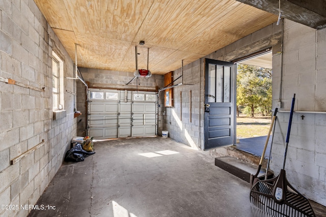 garage with a garage door opener, concrete block wall, and wooden ceiling