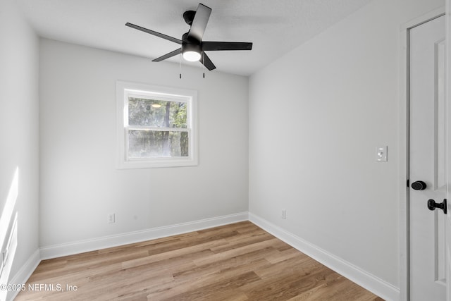 spare room featuring light wood finished floors, a ceiling fan, and baseboards