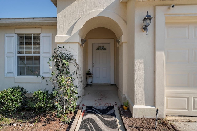 entrance to property with an attached garage and stucco siding