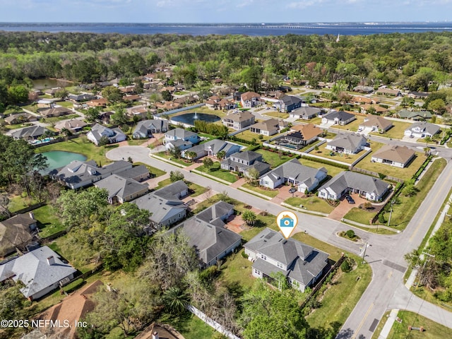 drone / aerial view with a water view, a residential view, and a view of trees