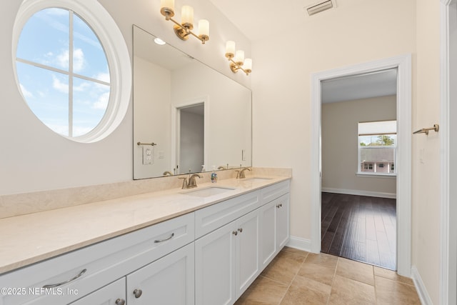 full bath with visible vents, a sink, baseboards, and double vanity