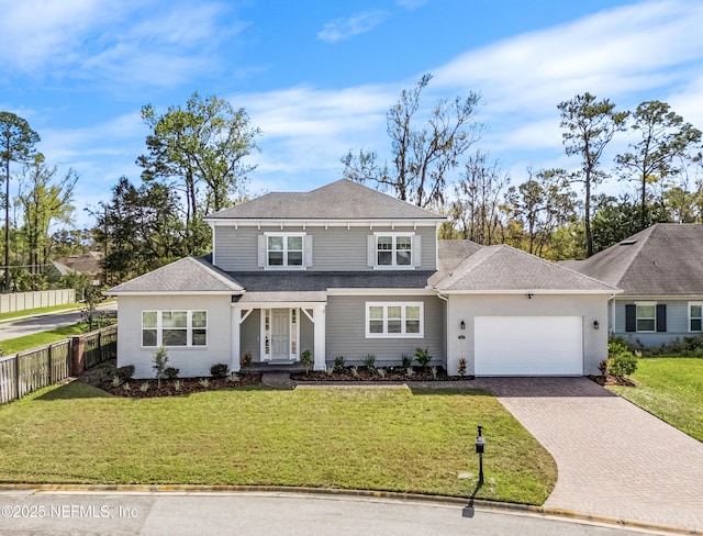 traditional-style home with a garage, decorative driveway, a front yard, and fence