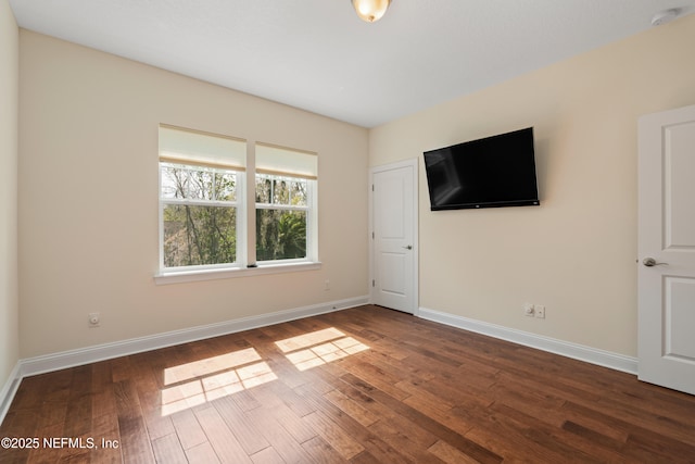 spare room with dark wood-style flooring and baseboards