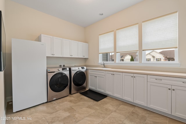 washroom with a sink, cabinet space, and washer and dryer