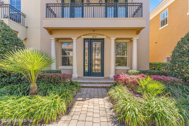 entrance to property with a balcony and stucco siding