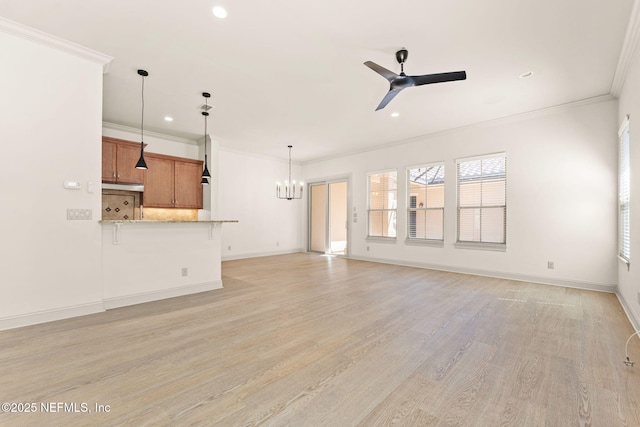 unfurnished living room with light wood-type flooring, baseboards, crown molding, and ceiling fan with notable chandelier