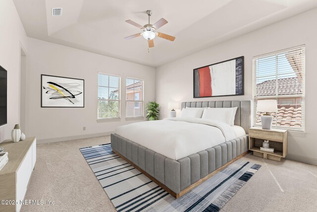 bedroom featuring a raised ceiling, visible vents, a ceiling fan, light carpet, and baseboards