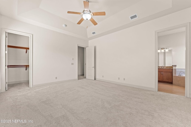 unfurnished bedroom featuring light carpet, a raised ceiling, and visible vents