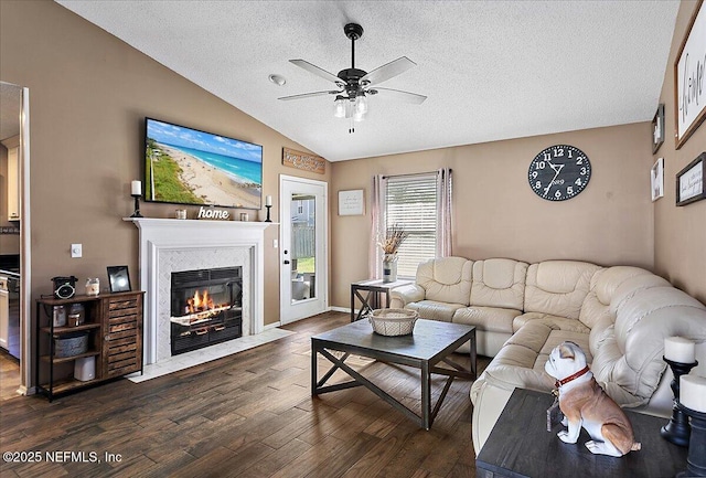 living area featuring a ceiling fan, lofted ceiling, dark wood-style floors, a textured ceiling, and a high end fireplace