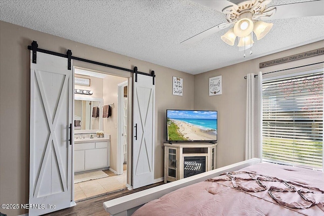 bedroom with a barn door, multiple windows, a ceiling fan, and a textured ceiling