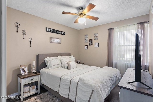 bedroom with a ceiling fan, dark wood-type flooring, and a textured ceiling