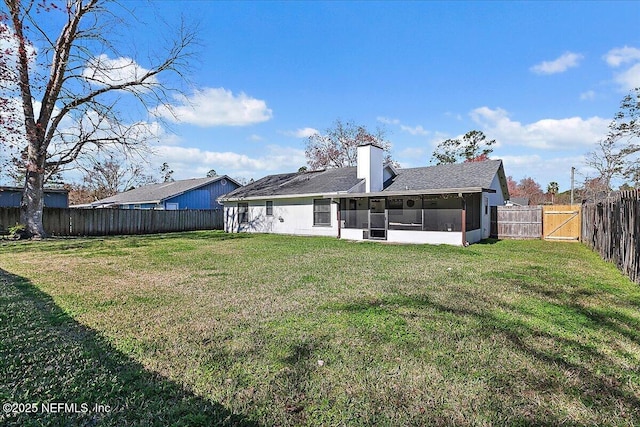 rear view of house with a sunroom, a fenced backyard, a chimney, a gate, and a yard