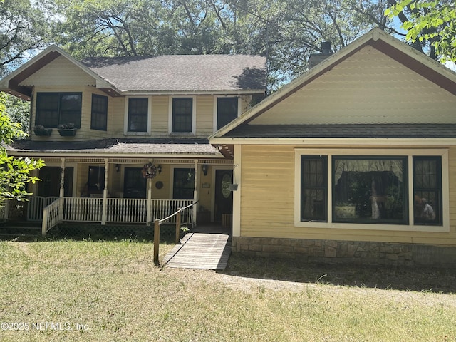 view of front of house featuring covered porch, a shingled roof, and a front lawn