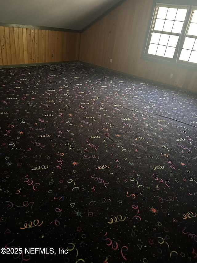 additional living space featuring carpet floors, vaulted ceiling, and wooden walls