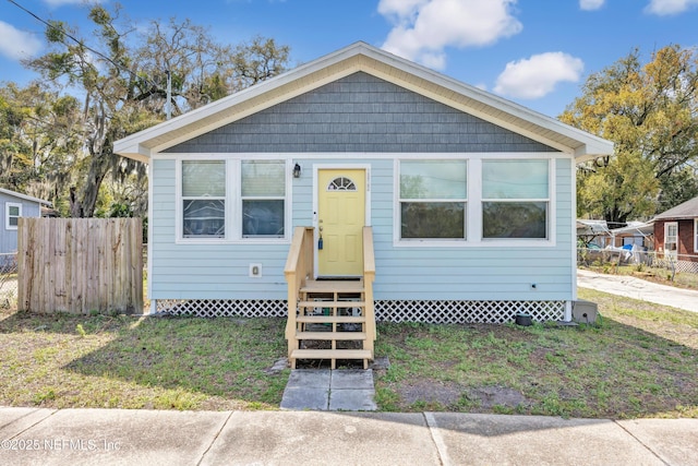 bungalow-style home featuring entry steps, a front yard, and fence