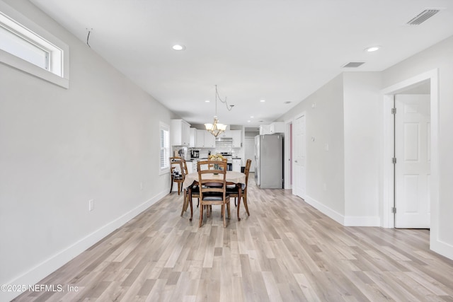 dining area featuring an inviting chandelier, a healthy amount of sunlight, visible vents, and light wood finished floors