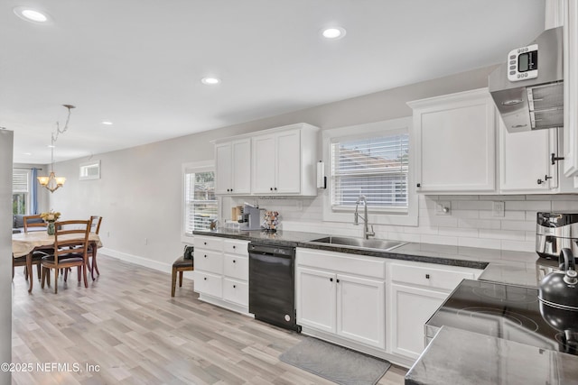 kitchen with light wood-style flooring, a sink, black dishwasher, white cabinetry, and tasteful backsplash