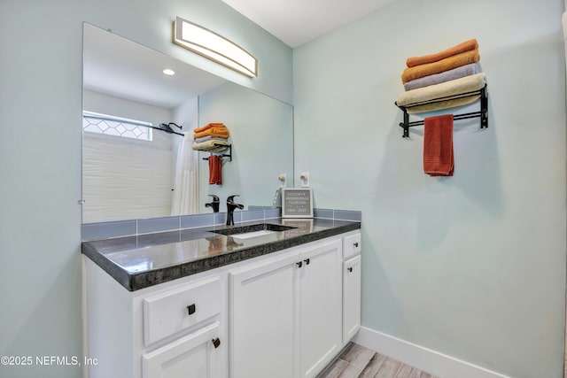 full bathroom featuring a shower with shower curtain, baseboards, wood finished floors, and vanity