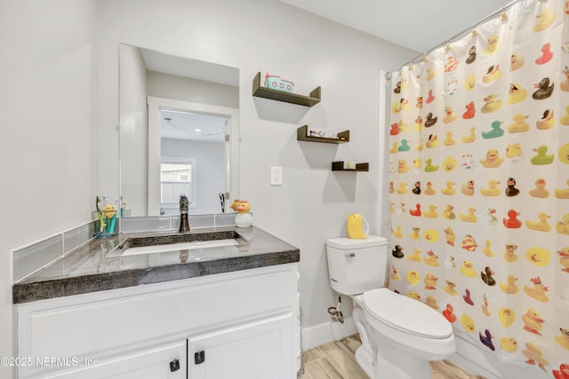 bathroom with vanity, a shower with curtain, wood finished floors, baseboards, and toilet