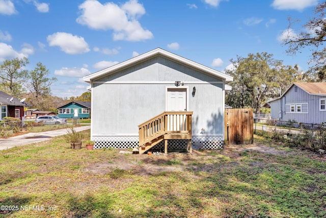 rear view of property featuring entry steps and fence