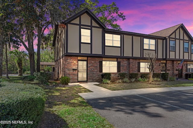 english style home with brick siding and stucco siding