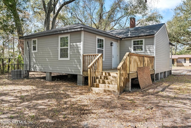rear view of house featuring a wooden deck and a chimney
