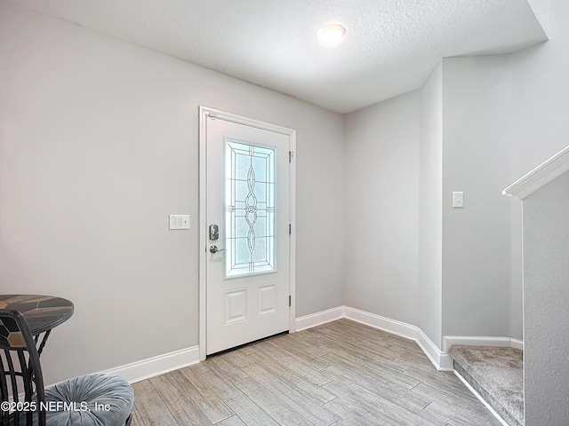 entrance foyer with a textured ceiling, light wood-style flooring, and baseboards